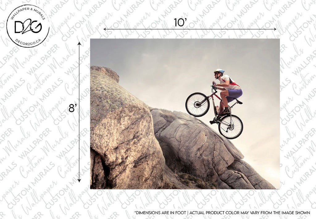 A cyclist in a helmet and sportswear is riding a mountain bike atop a large, rugged boulder under a cloudy sky, making it ideal as Decor2Go Wallpaper Mural. Dimensions and product color disclaimer are included.