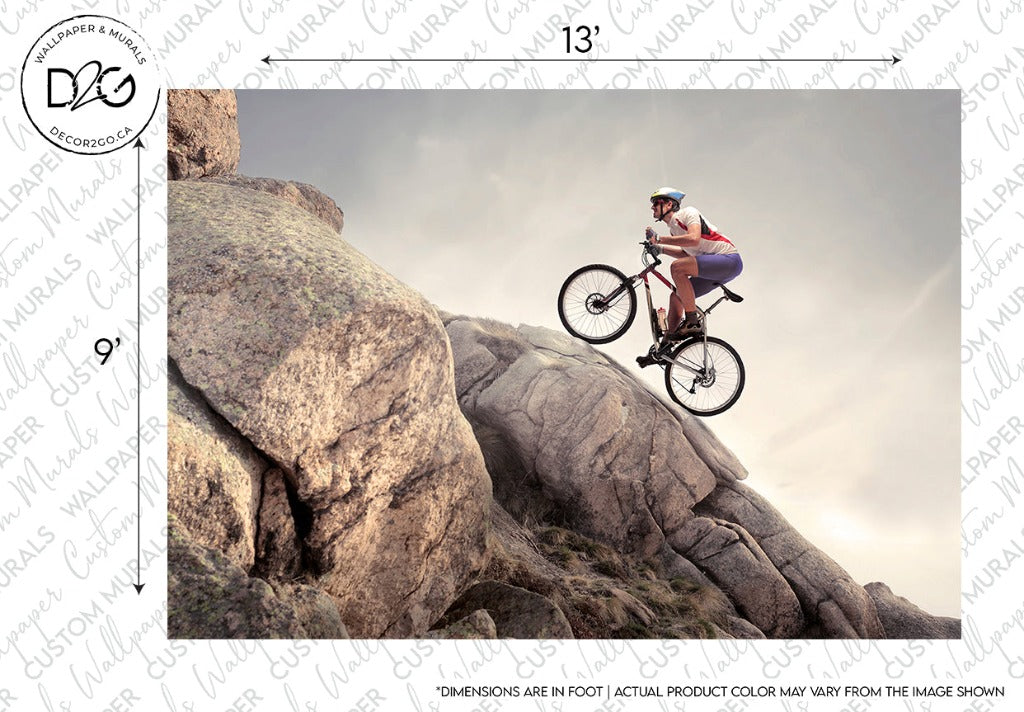 A cyclist in a red and white outfit performs a dramatic jump between large rocks under a clear sky, perfect for Decor2Go Wallpaper Mural, with a watermark and dimensions on the image's margin.