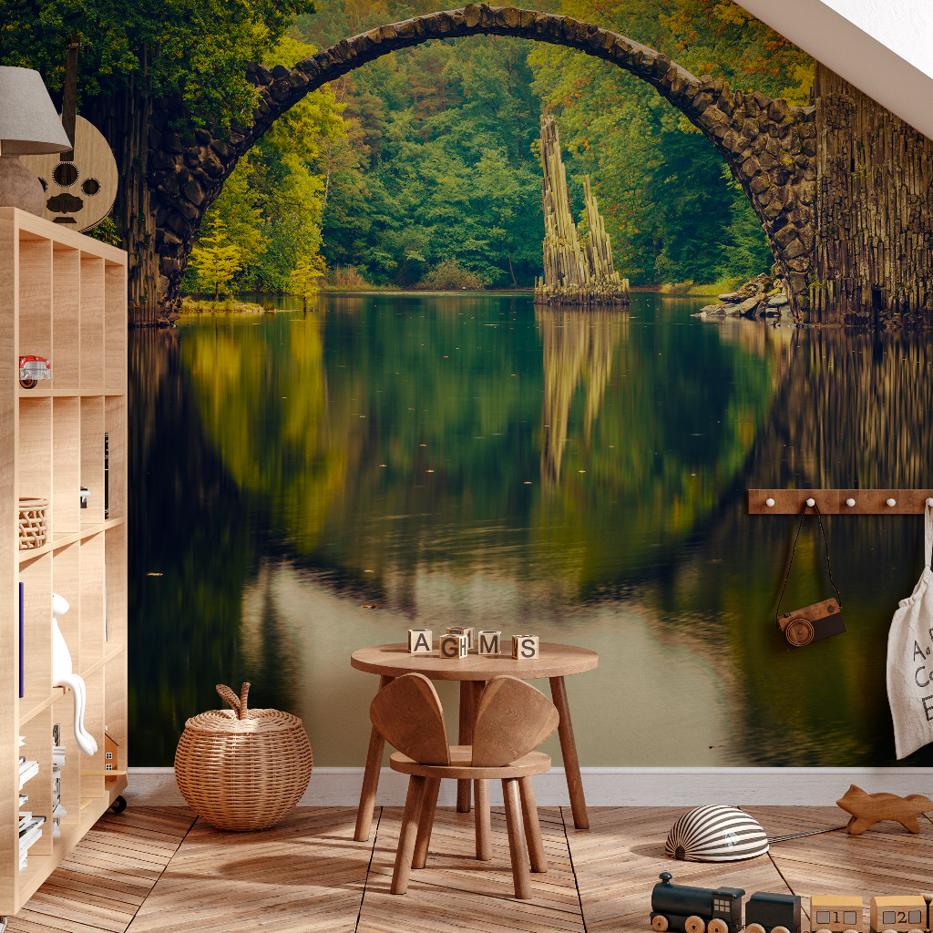 A cozy children's room with a Decor2Go Wallpaper Mural depicting a serene arch bridge over a reflective lake surrounded by autumn trees. There is a small wooden chair and toys neatly arranged on the hardwood floor.