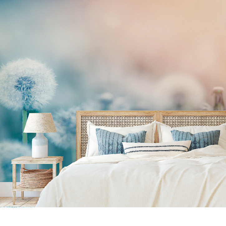 A serene bedroom featuring a large bed with white bedding and blue pillows, flanked by two wooden nightstands with lamps, set against a dreamy, pastel-colored Decor2Go Wallpaper Mural.