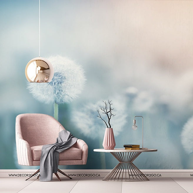 A serene living room setup featuring a soft pink armchair with a gray throw, a small round table with decorative items, and a Decor2Go Wallpaper Mural. A stylish circular wall mirror completes the airy.