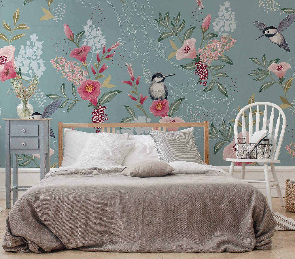 A cozy bedroom featuring a neatly made bed with gray bedding, set against a whimsical Decor2Go Wallpaper Mural with oversized floral designs, complemented by a light blue nightstand and a white wooden