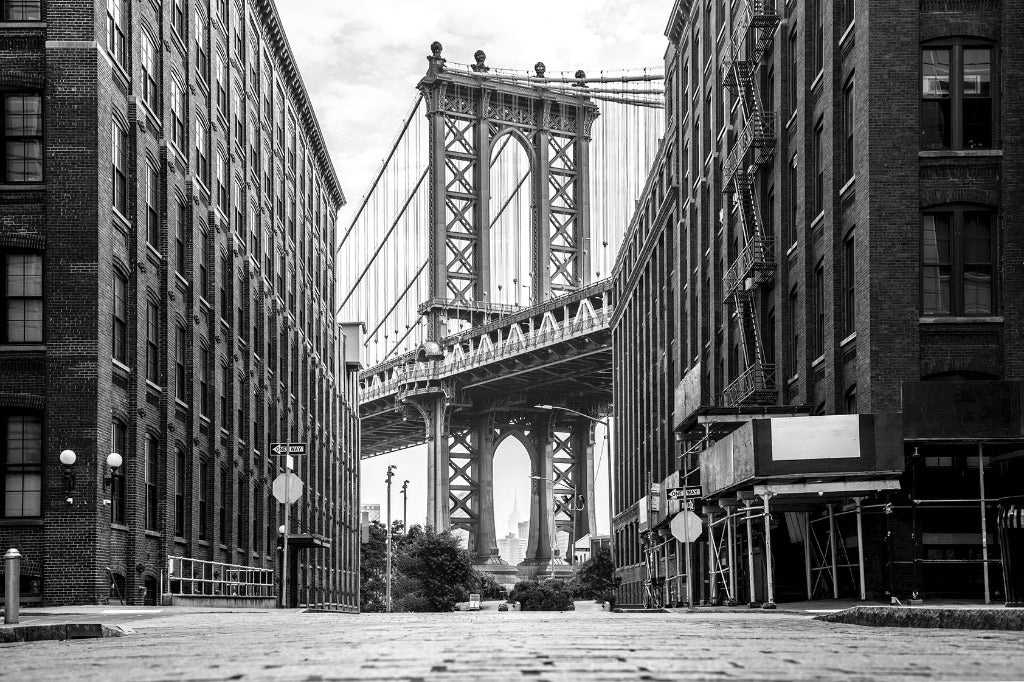 Black and white photo depicting the view of a towering Decor2Go Wallpaper Mural framed by old brick buildings on an empty street, capturing an urban, historic feel.