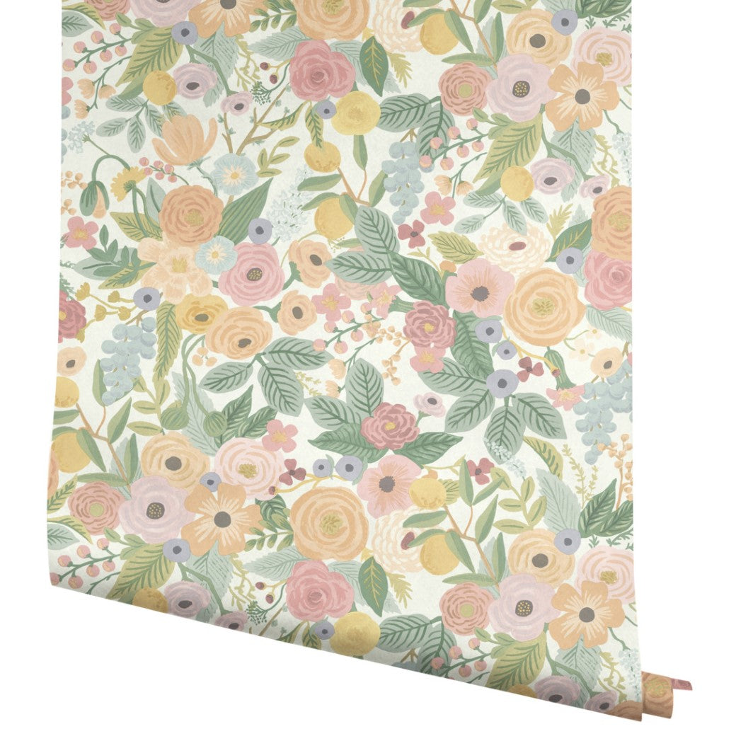 A roll of York Wallcoverings Pastels Garden Party Wallpaper (60 SqFt) features a colorful hand-painted floral pattern with pink, yellow, and peach flowers, green leaves, and berries on a white background.