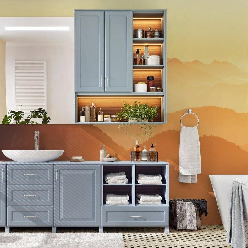 A well-lit bathroom with a blue cabinet, open shelves displaying toiletries, a white vessel sink, and a Decor2Go Wallpaper Mural depicting Sunset on the Mountains. Natural light flows through a window.