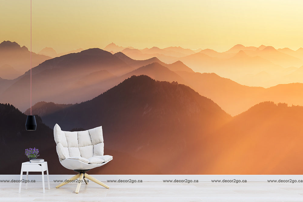 An elegant interior with a modern white chair and a small table with flowers next to a Decor2Go Wallpaper Mural depicting Sunset on the Mountains over layered mountain ranges.