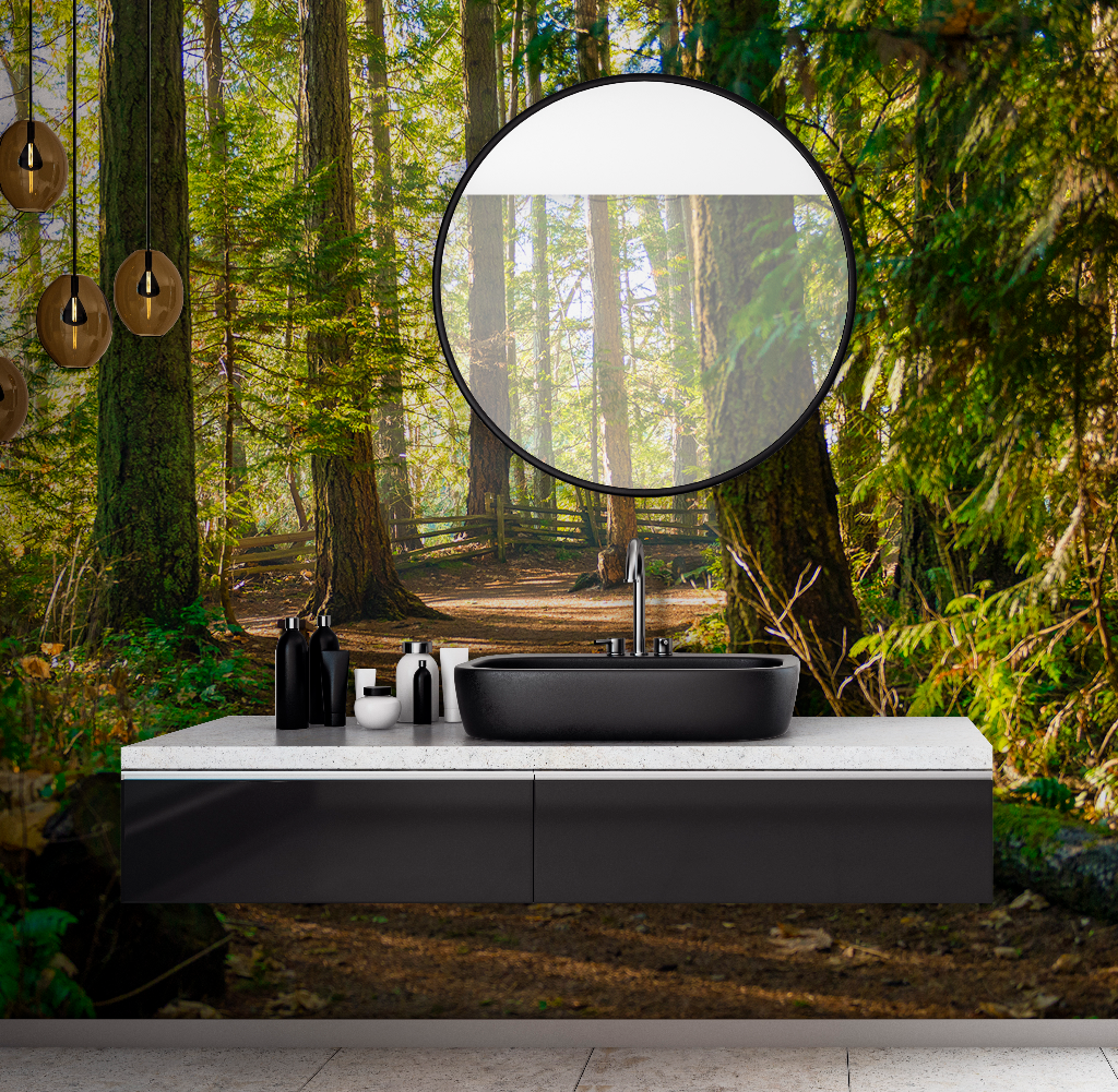 A modern bathroom vanity with a black basin set against a Forest Path Wallpaper Mural backdrop, viewed through a large circular mirror reflecting the trees and sunlight from Decor2Go Wallpaper Mural.
