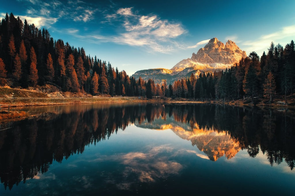 A Tranquil Lake Wallpaper Mural from Decor2Go Wallpaper Mural reflecting a majestic mountain surrounded by autumn-colored trees under a clear sky at sunset.