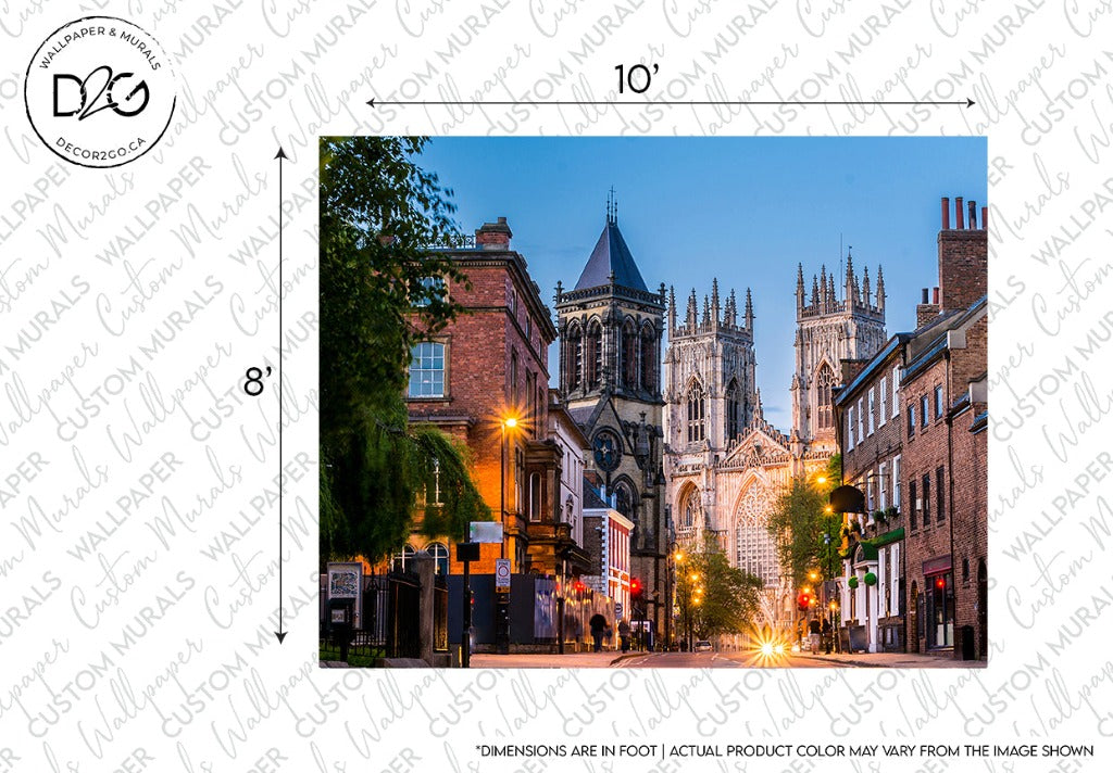A scenic view of a historic cathedral towering over surrounding brick buildings on a street lined with trees at twilight. The cathedral is elaborately illuminated, and the street is softly lit by street lamps, enhancing the Decor2Go Wallpaper Mural - England Stroll Wallpaper Mural.