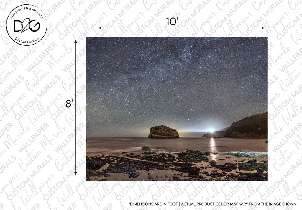 A night sky filled with stars over a serene beach with a large rock formation in the sea. Soft lighting illuminates the shore from the right side, creating a perfect scene for a Milky Way Galactic Coast Wallpaper Mural by Decor2Go Wallpaper Mural.