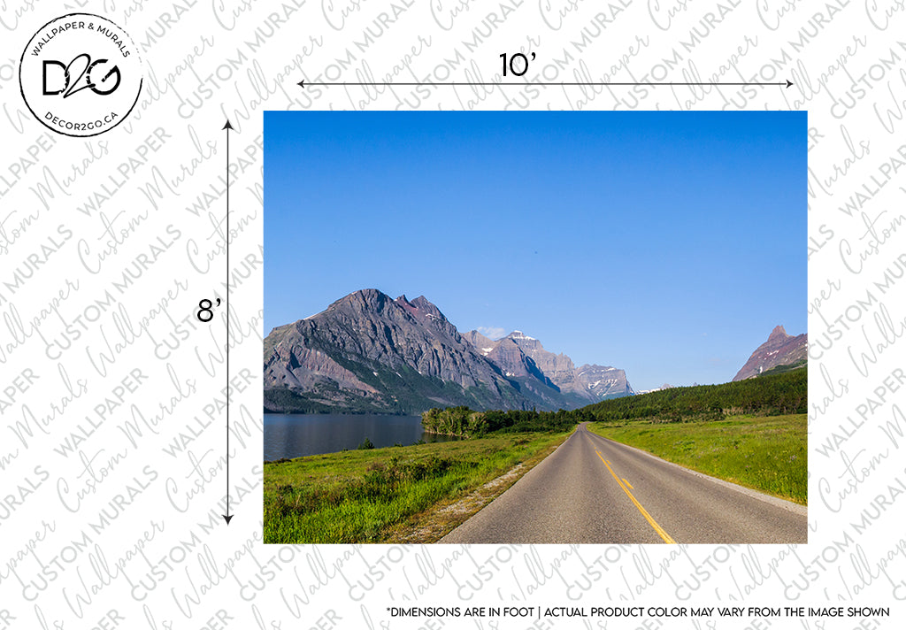 A road leading through a scenic landscape with a lake on the left and towering mountains in the distance under a clear blue sky. Watermark and measurement lines indicate a Decor2Go Wallpaper Mural feature wall mural catalog image of the Up, Up, and Away Wallpaper Mural.