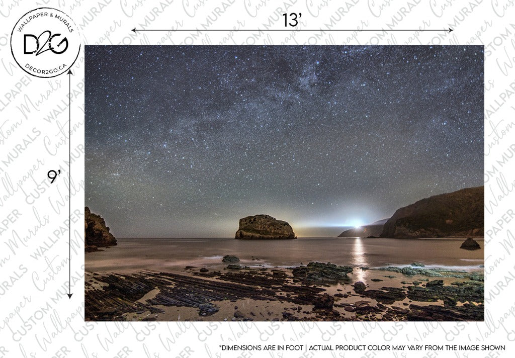 A night scene at a beach showing a starry sky above a rock formation in the sea, with gentle waves and reflections on the water, under a Milky Way Galactic Coast Wallpaper Mural on the top border by Decor2Go Wallpaper Mural.