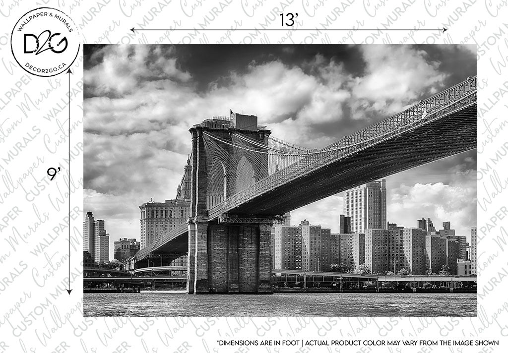 Black and white photo of the Decor2Go Wallpaper Mural Brooklyn Bridge Wallpaper Mural, an iconic landmark, with dramatic clouds above, extending towards a skyline featuring modern skyscrapers. A sample watermark text overlays the image.