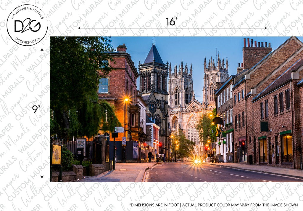 A scenic evening street view featuring a grand cathedral with spires in the background, illuminated buildings on either side, and a street lit by the headlights of an approaching car. This depicts historical architecture prominently in Decor2Go Wallpaper Mural's England Stroll Wallpaper Mural.