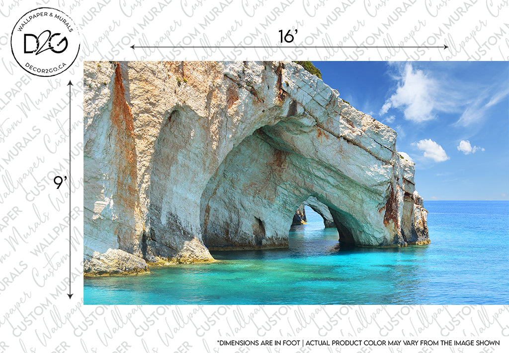 A panoramic view of the Aquatic Cavern Wallpaper Mural by Decor2Go Winnipeg, a large natural arch formation extending into a serene blue sea under a clear sky, indicating dimensions (16" x 9"). The rock formation is textured, sunlit, and features