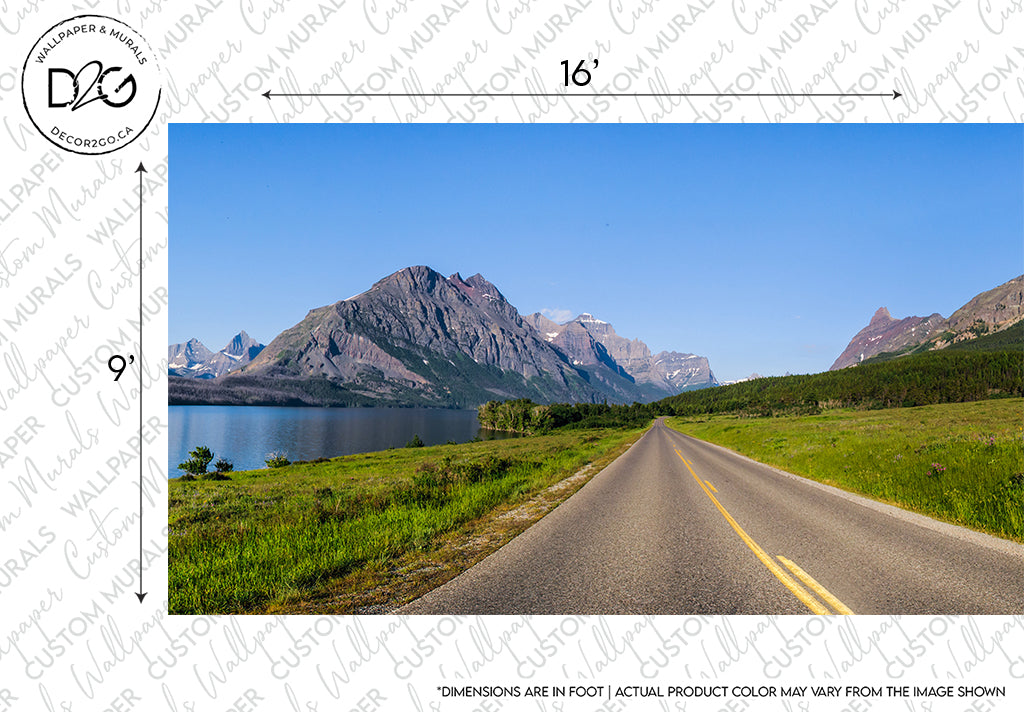A scenic road leading towards rugged mountains beside a lake, under a clear blue sky, with measurement markings and a logo on the image border designed as an Up, Up, and Away Wallpaper Mural by Decor2Go Wallpaper Mural.