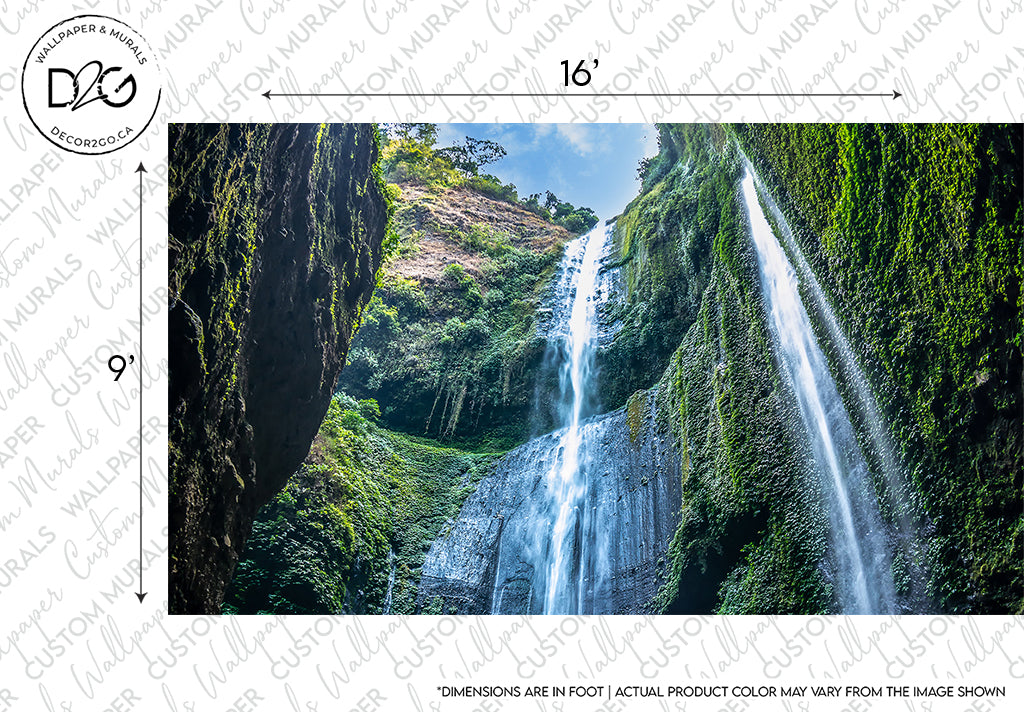 An image showing two tall, narrow waterfalls cascading down a lush, green cliffside, surrounded by dense foliage under a clear blue sky. Text and measurement overlays indicate design specifications for an Decor2Go Wallpaper Mural.