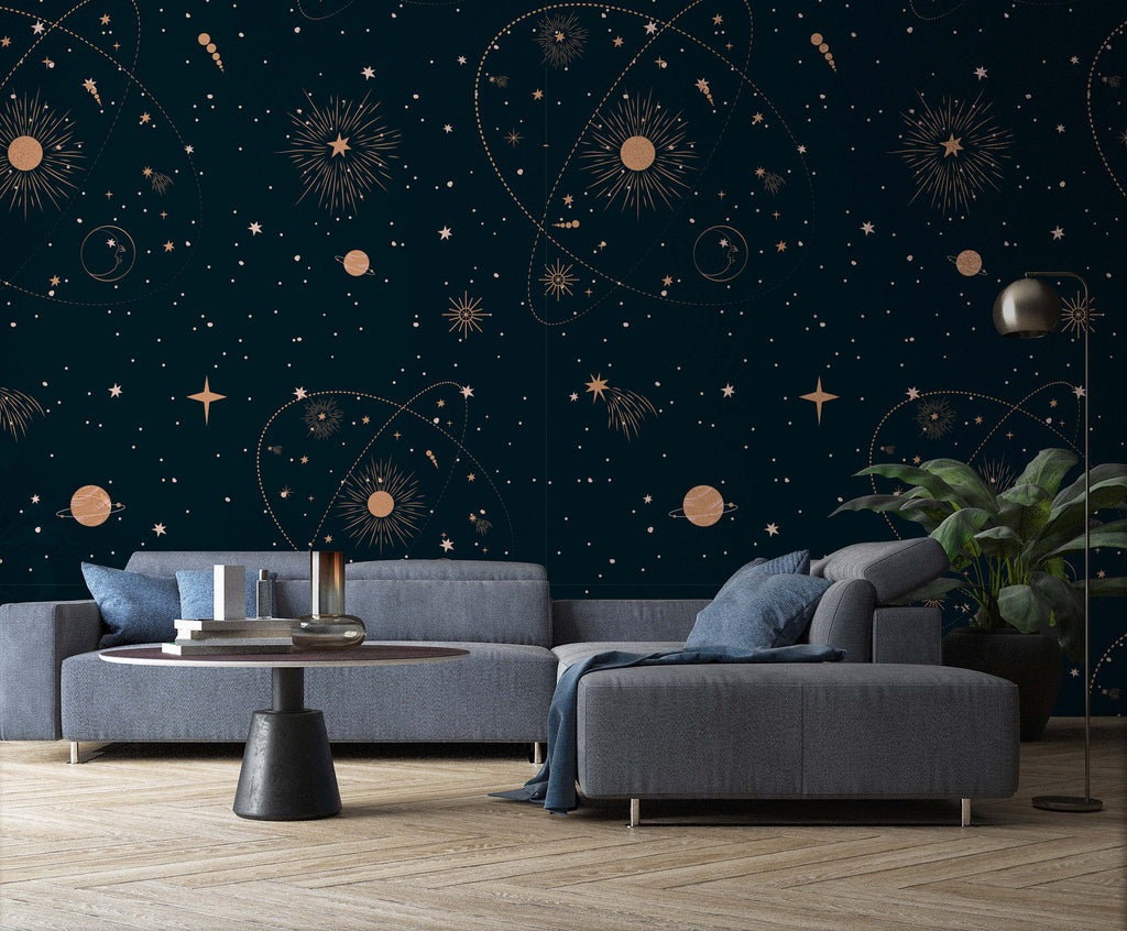 Modern living room with dark teal walls featuring gold celestial patterns, styled as a Decor2Go Wallpaper Mural. Includes a gray sectional sofa, round black coffee table, floor lamp, and a plant.