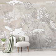Living Room - A living room wall covered with a Decor2Go Wallpaper Mural featuring delicate line drawings of various flowers. In front, a modern white armchair with green pillows and a small table with a plant.