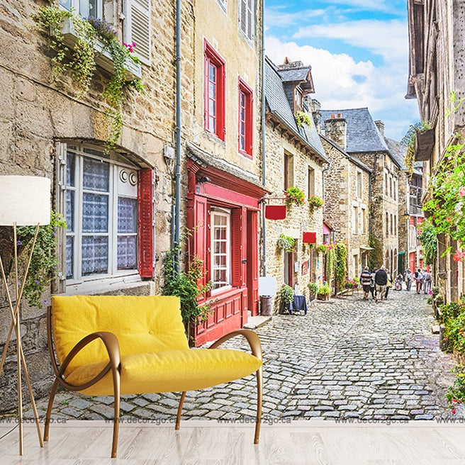 A vibrant European alley in a quaint town, featuring cobblestones, colorful houses with flowers, and a Decor2Go Wallpaper Mural Antique European Alley wallpaper mural with a lamp on the left foreground, blending reality with artistry.
