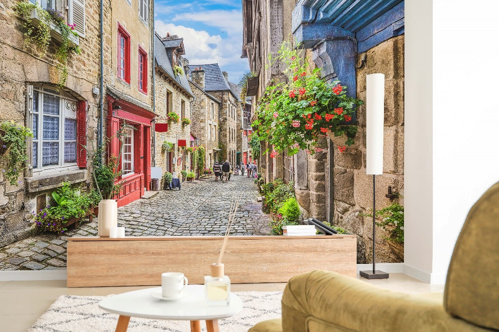 Living Room - A cozy living room with a large Decor2Go Wallpaper Mural depicting an Antique European Alley, with charming, old street with cobblestones and colorful flowering balconies, viewed from a sofa with a small table in front.