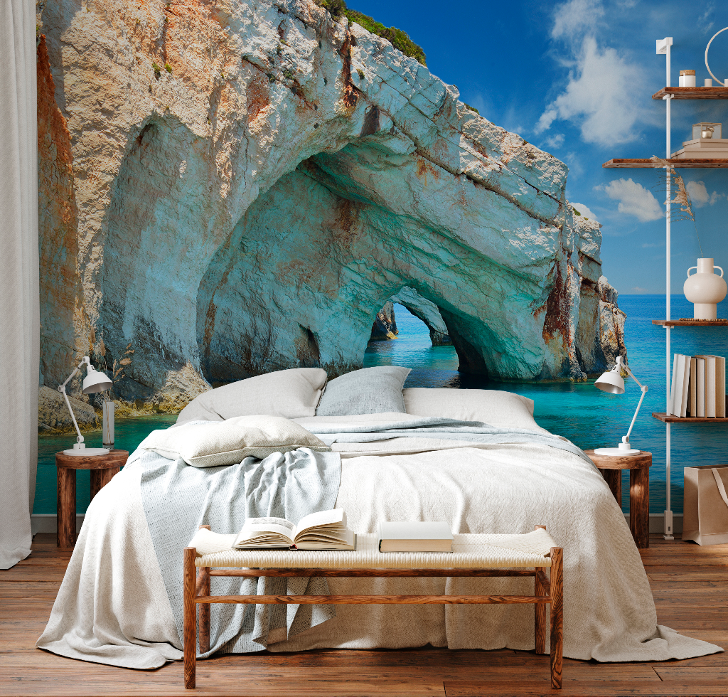 A cozy bedroom setup with an ocean-themed mural of an Aquatic Cavern Wallpaper Mural from Decor2Go Winnipeg behind the bed. The room includes a bed with white linens, side tables, and a rustic wooden bench.