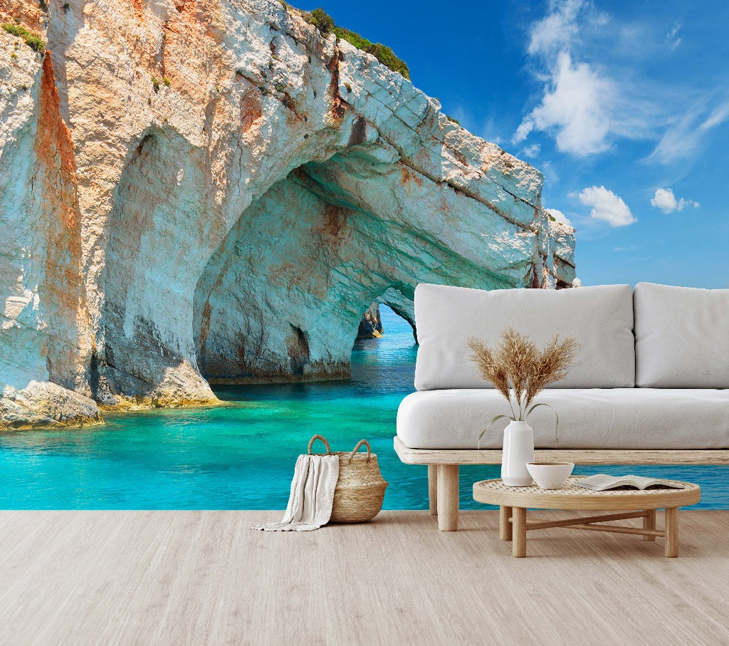A relaxing living room setup with a white sofa and coffee table facing a large Decor2Go Winnipeg Aquatic Cavern Wallpaper Mural depicting an underwater paradise and marine life. A straw bag and wooden floor complete the serene scene.