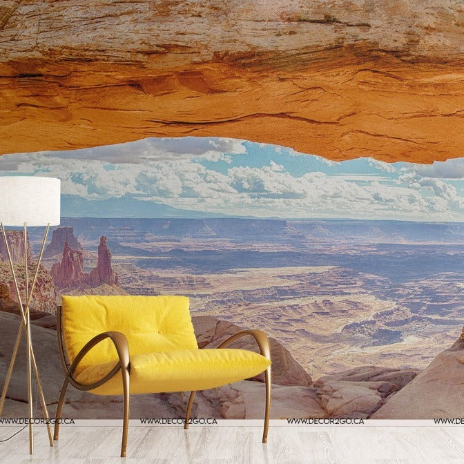 A vibrant interior featuring a yellow chair and a white lamp, set against a Decor2Go Wallpaper Mural on the walls, blending a luxurious living space with a rugged natural landscape.