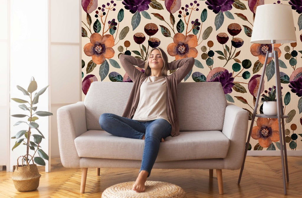 Living Room - A woman relaxes on a sofa with arms outstretched, legs crossed, in a cozy living room with Decor2Go Wallpaper Mural floral oil paint wallpaper and tasteful decor, including a floor lamp and potted plant.
