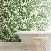 Bathroom - A features a white bathtub and a wicker basket, with the wall behind adorned in York Wallcoverings' Green Bali Leaves Wallpaper (60 SqFt) creating a tropical atmosphere. The light-colored flooring enhances the serene, nature-inspired theme