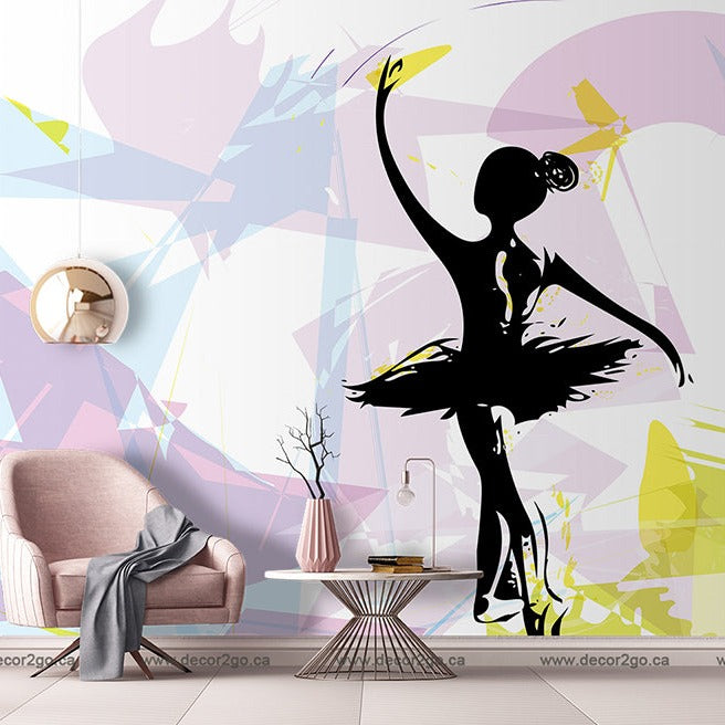 A stylish living room featuring a large, artistic Ballet Dancer Silhouette Wallpaper Mural of a black silhouette of a ballerina against an abstract, colorful background. The room includes a pink armchair, side table.