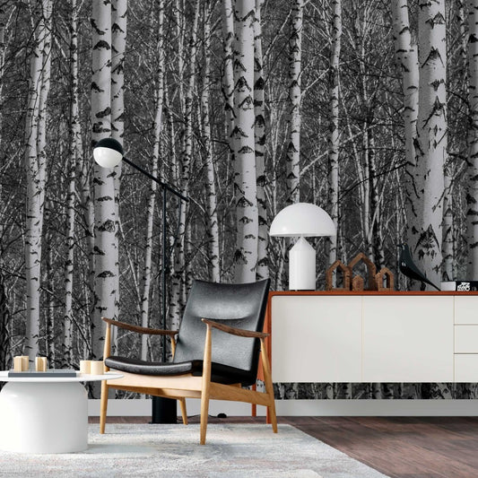 A stylish living room featuring Decor2Go Wallpaper Mural, modern furniture including a wooden chair with a grey cushion, a white storage unit, and minimalistic decor. A cozy lamp stands in the corner.