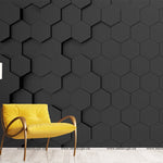 A minimalist living room with a stylish yellow armchair and a white floor lamp, set against a Decor2Go Wallpaper Mural Black Hexagons 3D Wallpaper Mural. The room has a modern and clean aesthetic.