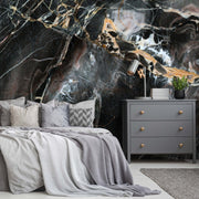 Bedroom - A modern bedroom featuring a large bed with gray bedding in front of a dramatic Decor2Go Wallpaper Mural black and gold marble wall. A gray dresser, small black side table, and houseplants complement the luxurious decor.