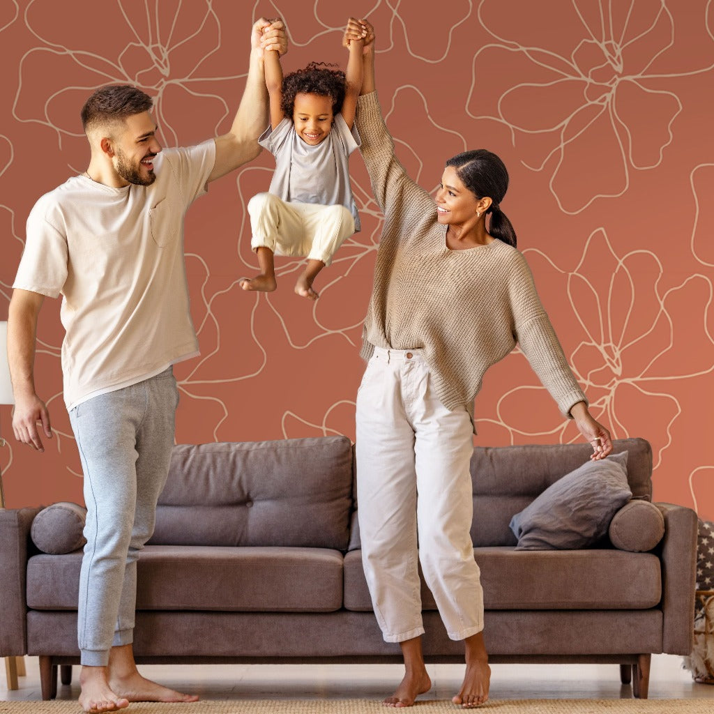 Living Room - A cheerful family with a man, a woman, and a child are playing together in a living room featuring customizable sizing options and Decor2Go Wallpaper Mural's Blossom Flower Lines Wallpaper Mural in the background. The tranquil atmosphere is highlighted as the man and woman lift the smiling child up by their arms.
