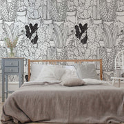 Bedroom - A cozy bedroom featuring a wooden bed with grey bedding, a white chair, a grey nightstand, and walls covered in Decor2Go Wallpaper Mural's Cactus Clan Wallpaper Mural.