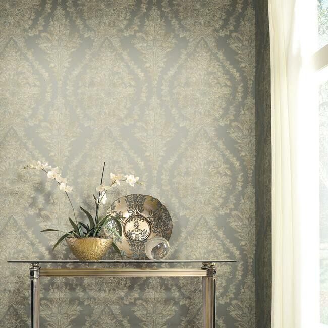 Elegant interior with a metallic table displaying decorative items including a vase with white flowers, a patterned plate, and a bowl, against Aqua Charleston Damask wallpapered wall beside a window with sheer curtains by York Wallcoverings.