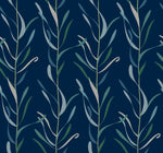 A seamless pattern features vertical, intertwining leafy vines in shades of green, blue, and beige on a dark blue background. The design is repetitive and symmetrical, creating an elegant and calming visual effect. This whimsical Chloe Vine Indigo Wallpaper Blue, Green (60 Sq.Ft.) by York Wallcoverings utilizes SureStrip technology for easy application and removal.