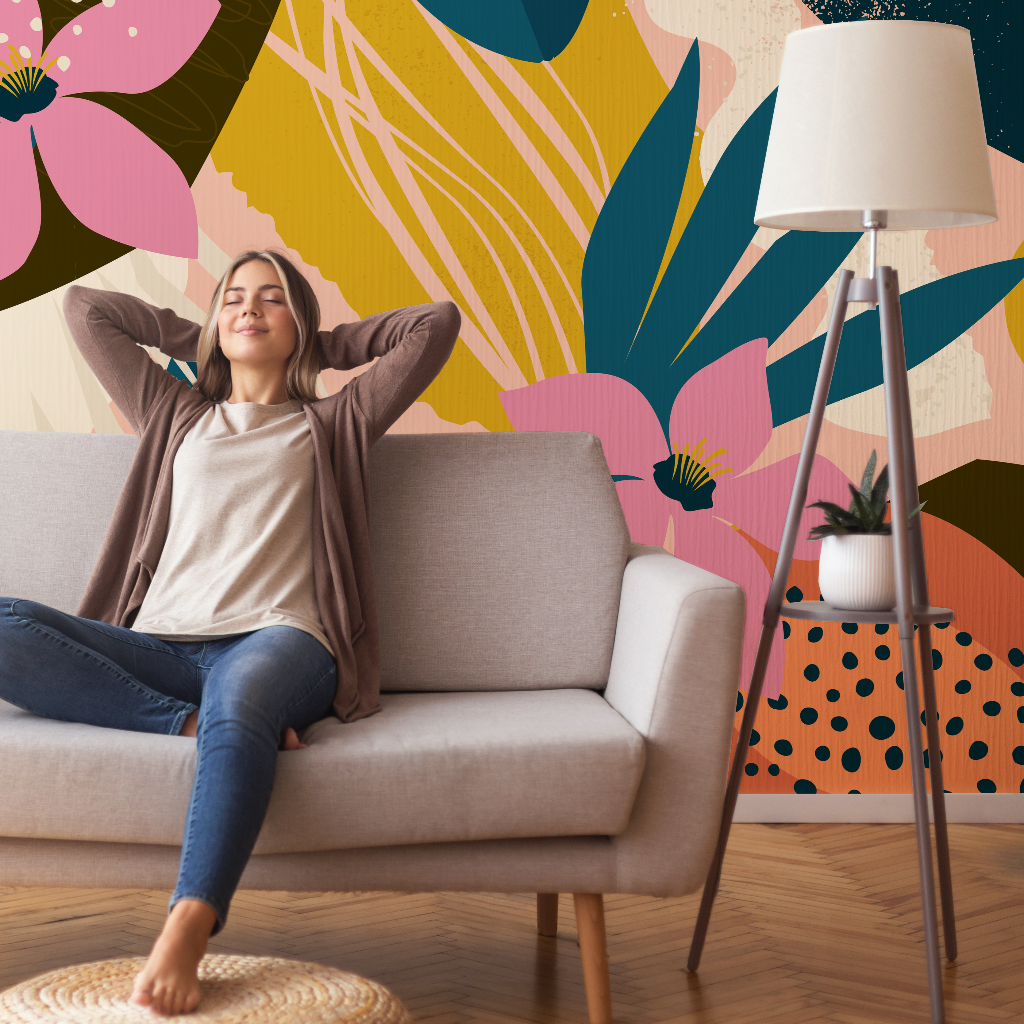 Living Room - A young woman relaxes on a sofa with her eyes closed and hands behind her head in a vibrant, colorful living room with a Collage Contemporary Floral Wallpaper Mural by Decor2Go Wallpaper Mural and a floor lamp.