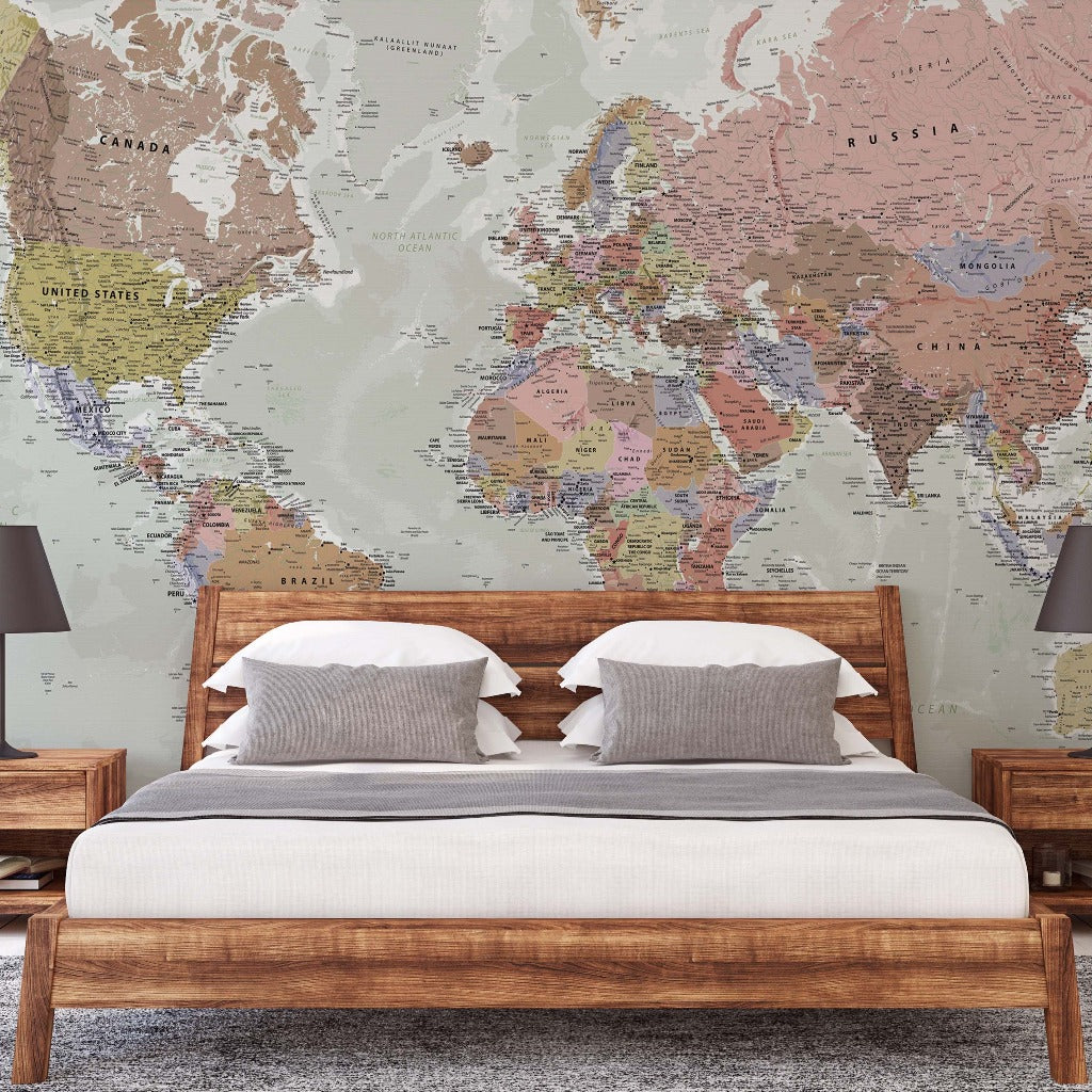 A travel enthusiast's bedroom featuring a large Decor2Go World Map Wallpaper Mural behind a wooden bed with white and beige bedding, flanked by two wooden nightstands with lamps.