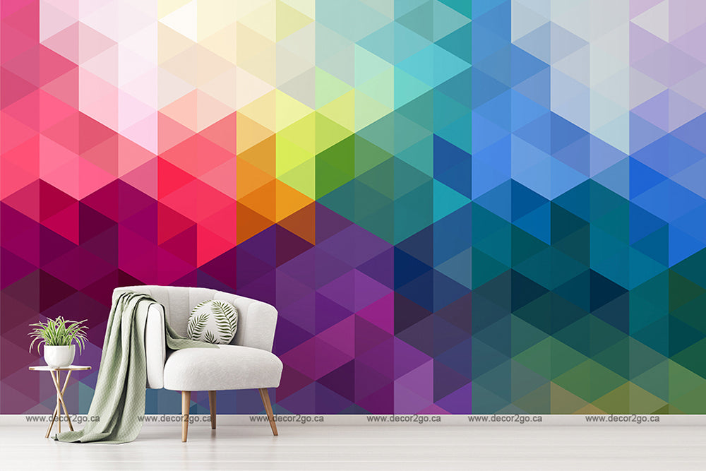 A modern interior with a vibrant, Decor2Go Wallpaper Mural of Colorful Triangular Patterns and a stylish chair with a gray cushion and green throw blanket next to a small white side table.