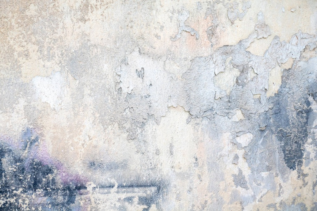 Aged and weathered wall with Cracked Paint Wallpaper Mural from Decor2Go Wallpaper Mural, featuring cracked blue paint and subtle patches of discoloration, textures ranging from flaking layers to smooth patches with a hint of purple graffiti on the left side.