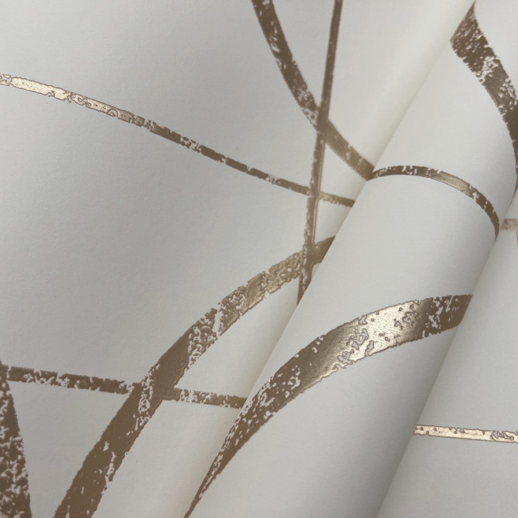 The Cream & Gold Sprigs Wallpaper by York Wallcoverings features an elegant design with abstract intersecting lines forming geometric shapes. The metallic gold texture on a light beige background creates a modern decorative pattern, ideal for stylish interiors.