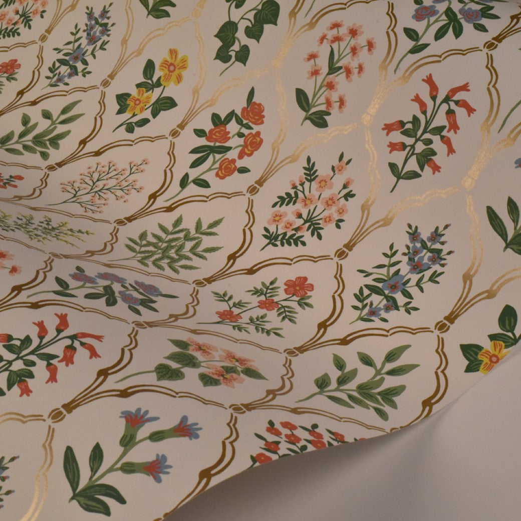 The Cream Hawthorne Wallpaper by York Wallcoverings (60 SqFt) features a crisp white background adorned with ornate gold lattice patterns and colorful, hand-painted floral designs inspired by vintage wallpaper.