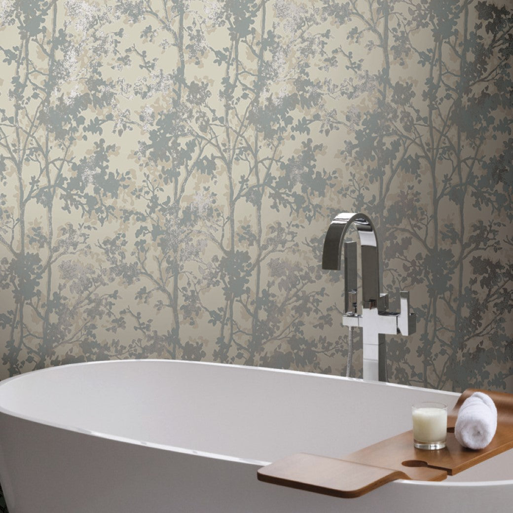 A minimalist bathroom showcases a white freestanding bathtub with a chrome faucet. A wooden bath tray holds a candle and towel, while the wall features York Wallcoverings' Cream & Silver Shimmering Foliage Wallpaper in gray and beige tones.