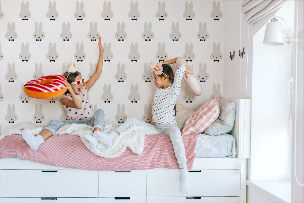 Girls playing in their room with  cute rabbit wallpaper 
