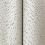 Close-up of York Wallcoverings Dew Drop Beige Wallpaper (60 SqFt), featuring light-colored, textured non-woven material with small, irregular raised dashes in curved lines for a subtle, elegant look.