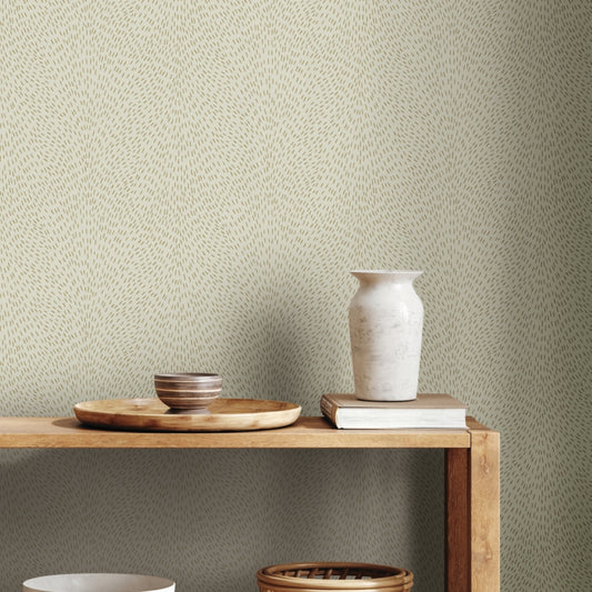 A wooden shelf with a tray, striped bowl, white ceramic vase, and books is set against York Wallcoverings Dew Drop Beige Wallpaper (60 SqFt) featuring a light beige background with a subtle dotted pattern.