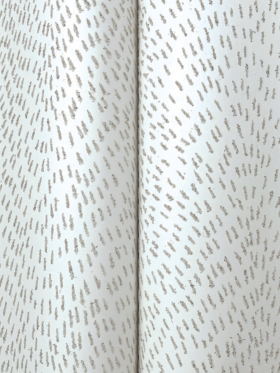 A close-up of York Wallcoverings' Dew Drop White Wallpaper (60 SqFt) shows metallic silver fabric with small, evenly spaced textured dashes in a subtle, repeating pattern and a vertical central seam—evoking the look of glitter wallpaper.