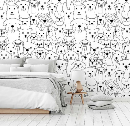 A modern bedroom with a Decor2Go Wallpaper Mural featuring various cartoon dog faces in black and white. The room has a bed with gray bedding, a small wooden bedside table, and a floor cushion.